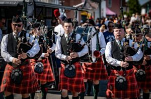 Traditional Scottish bagpipers in kilts performing at a lively outdoor event in the UK.